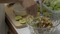 Housewife squeezed lemon juice then using spoon and fork mixing all ingredients in a big bowl.