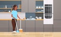 Housewife sweeping floor with broom and scoop african american girl doing housework house cleaning concept modern Royalty Free Stock Photo