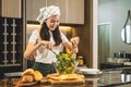 Housewife using ladle to scoop vegetable salad onto a plate after mixing fresh vegetable salad in bowl while standing