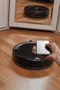 Housewife using mobile to control robotic vacuum cleaner before mirror in bedroom Royalty Free Stock Photo