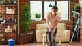 Housewife using vacuum cleaner to tidy up living room