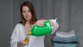 The housewife washes clothes. A young woman pours liquid washing powder.