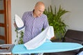 Housework and household concept - man ironing shirt on iron board at home. Royalty Free Stock Photo