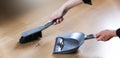 Housework and housekeeping concept. Close up of woman with brush and dustpan sweeping floor at home. Wide banner copy