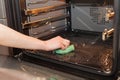 Housework and housekeeping concept. Scrubbing the stove and oven. Female hand with green sponge cleaning the kitchen oven. Royalty Free Stock Photo