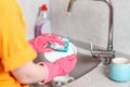 Housework. A housewife in pink rubber gloves is washing a plate. Close up of kitchen sink and hands. View from the shoulders Royalty Free Stock Photo