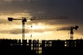 Silhouettes of two tower cranes over unfinished building at sunrise Royalty Free Stock Photo
