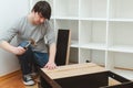 Housing furniture theme. Contractor repairman assembling new furniture in modern apartment