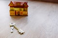 Housing keys next to a miniature house on a floor, negative space Royalty Free Stock Photo