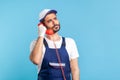 Housing maintenance call centre. Attentive handyman in overalls, safety gloves, holding retro phone handset Royalty Free Stock Photo