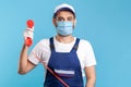 Housing maintenance call centre. Friendly handyman in overalls, safety gloves, holding retro phone handset Royalty Free Stock Photo