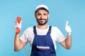 Housing maintenance call centre. Satisfied handyman in overalls, safety gloves, holding retro phone handset