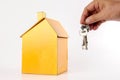 Housing/real estate concept. Hand holds key and house model on white. Royalty Free Stock Photo