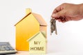 Housing/real estate concept. Hand holds key and house model on white. Royalty Free Stock Photo