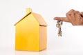 Housing/real estate concept. Hand holds key and house model on white. Royalty Free Stock Photo