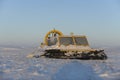 Hovercraft and arctic fox in winter tundra. Air cushion on the beach. Yellow hover craft under snow
