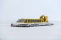 Hovercraft in winter tundra. Air cushion on the beach. Yellow hover craft under snow