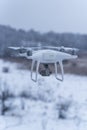 Hovering drone taking pictures of wild nature. Cold winter weather. Cloudy day with falling snow Royalty Free Stock Photo