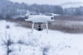 Hovering drone taking pictures of wild nature. Cold winter weather. Cloudy day with falling snow Royalty Free Stock Photo