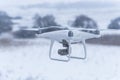 Hovering drone taking pictures of wild nature. Cold winter weather. Cloudy day with falling snow Royalty Free Stock Photo