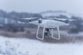 Hovering drone taking pictures of wild nature. Cold winter weather. Cloudy day with falling snow Royalty Free Stock Photo