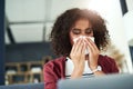 How can I treat the flu at home. a young woman blowing her nose while using a laptop on the sofa at home. Royalty Free Stock Photo