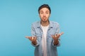 How could you? Portrait of man in denim shirt looking angry and surprised, raising hands with indignant expression