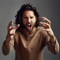 How dare you. Studio shot of a young man screaming in anger against a gray background. Royalty Free Stock Photo