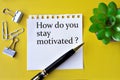 HOW DO YOU STAY MOTIVATED? - words on a white sheet with a pen, stationery clips and a cactus Royalty Free Stock Photo