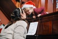 This is how little Santa Claus gives an applause. a young woman playing the piano for her sons at Christmas. Royalty Free Stock Photo