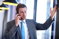 How long do you expect me to wait. a handsome young businessman talking on his mobile phone at work. Royalty Free Stock Photo