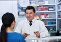 How may I help you. a male pharmacist helping a female customer in a pharmacy. Royalty Free Stock Photo