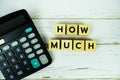 How Much? with wooden blocks alphabet letters and calculator on wooden background Royalty Free Stock Photo