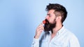 That is how tastes summer. Man handsome hipster with long beard eating strawberry. Hipster enjoy juicy ripe red