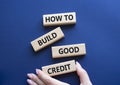 How to build good credit symbol. Concept words How to build good credit on wooden blocks. Beautiful deep blue background.