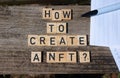 How to create a NFT? Black capital letter words on wooden toy blocks on a natural garden table background with paper and pencil.
