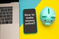 How to make money online - concept of passive income with message on a mobile phone. Moneybox near laptop and mobile