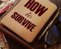 How to survive words on cover of copybook, glasses and pen. Surcvival concept. Crisis management business concept Royalty Free Stock Photo