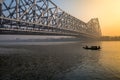 Howrah bridge Kolkata at dawn with wooden boat on river Hooghly.