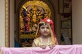 Howrah,India -October 26th,2020 : Bengali girl child posing with Goddess Durga in background, inside old age decorated home. Durga