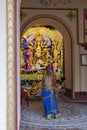 Howrah,India -October 26th,2020 : Bengali girl child posing with Goddess Durga in background, inside old age decorated home. Durga