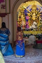 Howrah,India -October 26th,2020 : Bengali girl child taking picture of Goddess Durga inside old age decorated home. Durga Puja,
