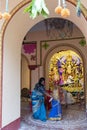 Howrah,India -October 26th,2020 : Bengali sari clad mother, showing Goddess Durga to child, Durga inside old age decorated home.