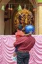 Howrah,India -October 26th,2020 : Father with helmet on, showing Goddess Durga to his child, Durga inside old age decorated home.