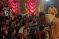 Hindu purohit drawing tilak, holy sign on forehead of Hindu devotees worshipping Goddess Durga, inside decorated Durga Puja Pandal