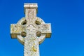 Old stone celtic cross on a bright clear blue sky background with empty copy space for text Royalty Free Stock Photo