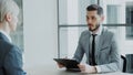 HR male manager having job interview with young woman in suit and watching her resume application in modern office Royalty Free Stock Photo