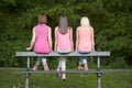 Hree young female friends seated on a bench, outdoors