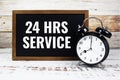 24 HRS Service text message with alarm clock on wooden background