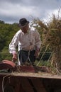 HRUSOV, SLOVAKIA - AUGUST 16: Old farmer in traditional costume fills the thresher during folklore festival Hontianska Parada on Royalty Free Stock Photo